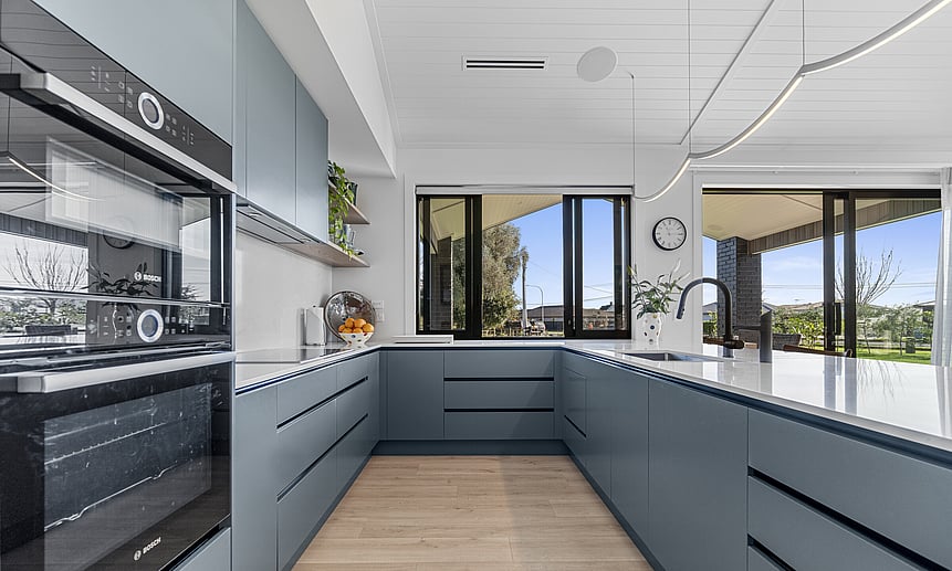 The sleek modern kitchen has marble benchtops & a slider kitchen window for entertaining guests in this Cambridge new build. 