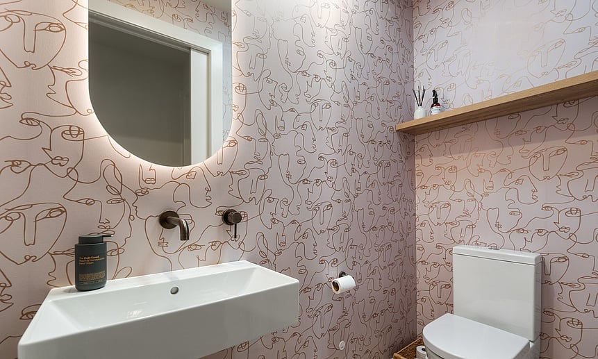 Silhouettes of faces adorn this feature wall, while mirror lighting creates a soft glow in this unique toilet design.