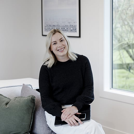 Nikki Jones is head Admin in charge of house design and Owner of Linecrest Homes. She is leaning on the couch and smiling.