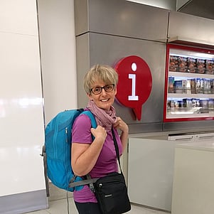 Woman with bag standing at airport information desk.
