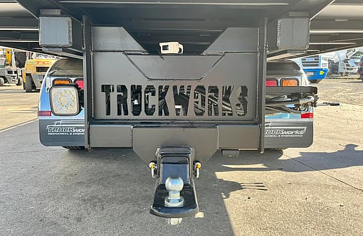 Custom fabricated metal plate at rear of Fuso Canter salvage truck. Metal is cut out and reads "TRUCKWORKS"