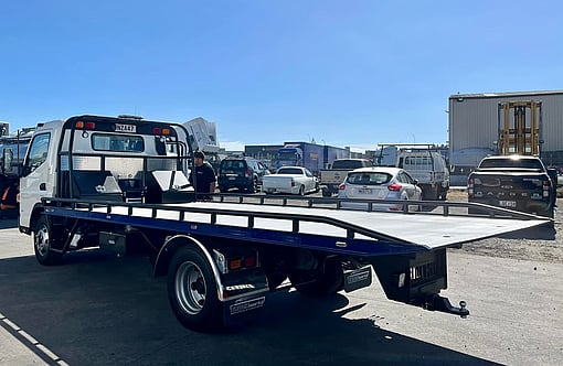 Rear passenger view of Fuso Canter salvage truck. Custom fabricated slide deck and subframe is in view, along with custom LED lighting, truckworks mud flaps, and custom tool box