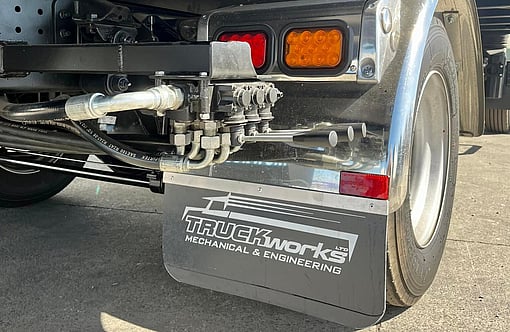 Photo of Fuso Canter salvage truck rear drivers side wheel. Hydraulic lift kit and Truckworks mudflaps are visible.