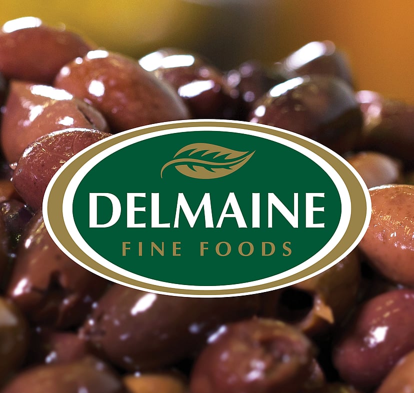 A green and gold Delmaine logo design over a close up of Spanish olives.
