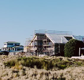 Exterior of a bespoke architectural coastal home on Ocean Beach Road in Mount Maunganui with framing and scaffolding visible during construction by MB Construction.