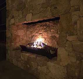 Living room with stone fireplace and full-height glazing in the Ocean Beach Road architectural coastal home in Mount Maunganui, built by MB Construction.
