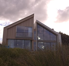 Ocean Beach Road architectural coastal home exterior at sunset with cedar cladding and large glazing overlooking the dunes in Mount Maunganui, built by MB Construction.