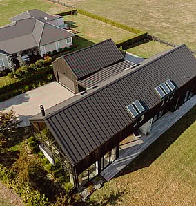 Aerial view of barn-style architectural rural home near Matamata with cedar cladding, gabled barn form and surrounding rural landscape, built by MB Construction, residential builders for Matamata and the Bay of Plenty.