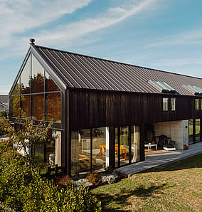 Barn-style architectural rural home near Matamata with cedar cladding and north-facing gabled elevation opening to the lawn and rural outlook, built by MB Construction, residential builders for Matamata and the Bay of Plenty.