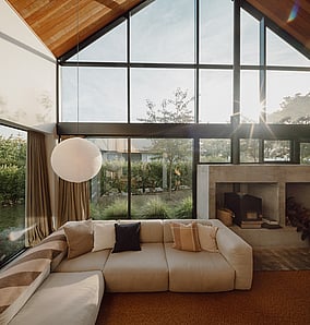Double-height living room in an architectural rural home near Matamata with full-height glazing to the rural outlook and concrete fireplace, built by MB Construction, residential builders for Matamata and the Bay of Plenty.