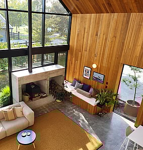 Living room in an architectural rural home near Matamata with mezzanine overlook, concrete fireplace and built-in window seat framing the rural outlook, built by MB Construction, residential builders for Matamata and the Bay of Plenty.