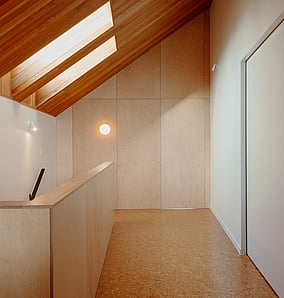 Upper landing in an architectural rural home in Matamata with raked timber ceiling, skylights and full-height plywood wall concealing a secret room, built by MB Construction.