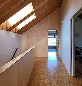 Plywood feature wall and secret room doorway on the upper landing of an architectural rural home in Matamata by MB Construction.