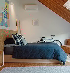 Architectural rural home bedroom in Matamata with raked timber ceiling, skylights and cork flooring, designed and built by MB Construction.