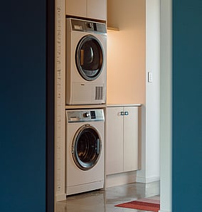 Laundry in an architectural rural home in Matamata with dark blue joinery, timber shelving and external access, designed and built by MB Construction.