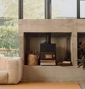 Concrete fireplace with integrated firewood niche in the living space of an architectural rural home in Matamata, designed and built by MB Construction.