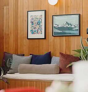 Living area in an architectural rural home in Matamata with timber-panelled bench seating and concrete fireplace, built by MB Construction.