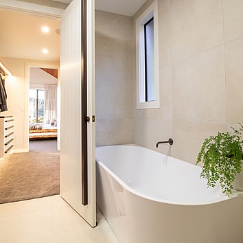 Modern bathroom with open door and freestanding bath. 