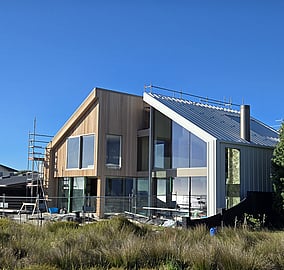 Daytime exterior of bespoke architectural beach home on Ocean Beach Road with sand dunes in front, built by MB Construction.