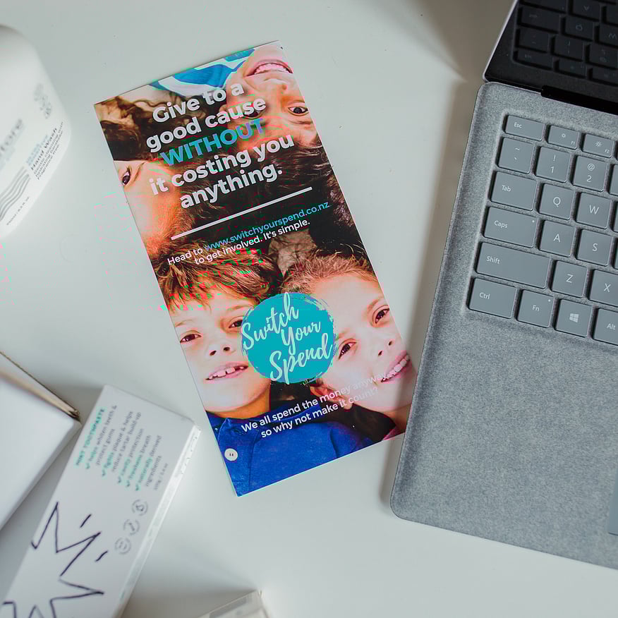 Leaflet for Switch Your Spend showing two children smiling with a laptop and product packaging nearby