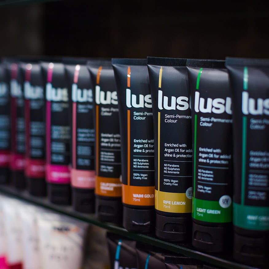 Various shades of semi-permanent hair dye in black tubes with labels displaying the product name and details