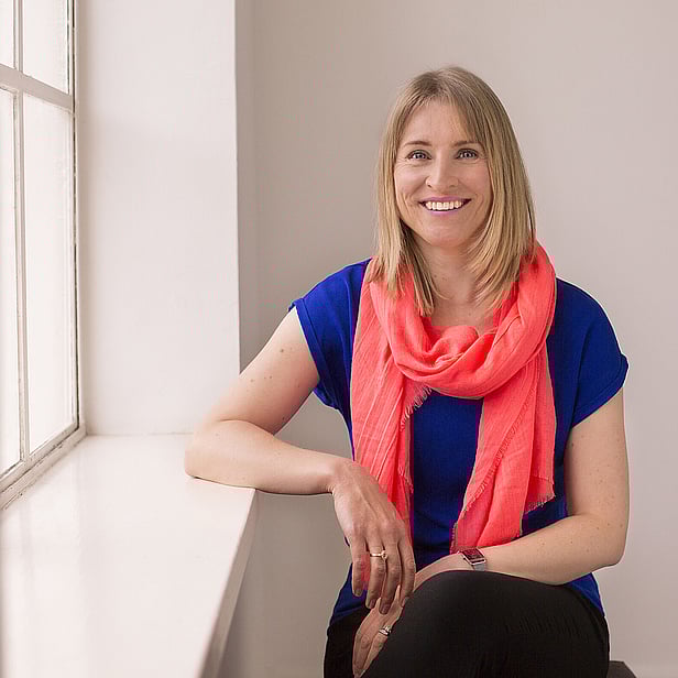 Renee Murphy, Brand messaging strategist. Sitting, looking at the camera, relaxed and smiling wearing an electric blue top and a bright orange scarf