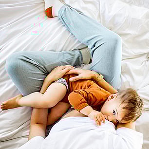 Childrens fashion photography for Kauri and Sons Overhead baby breastfeeding in bed