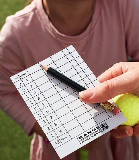 Holding a mini golf scoring card with pencil and golf ball in hand