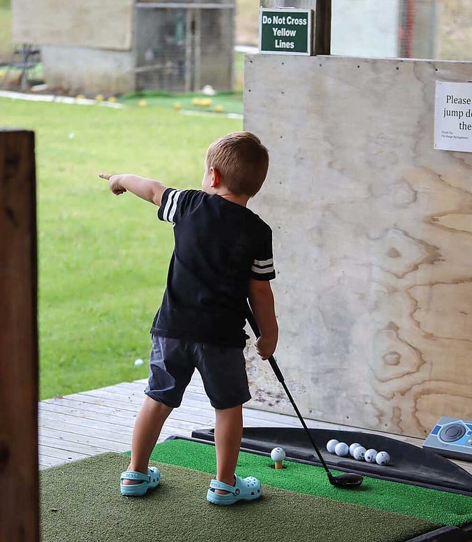 Driving range little boy pointing with golf club
