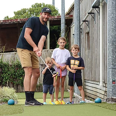 Dad and three kids playing mini golf together