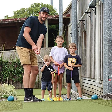 Dad and three kids playing mini golf together
