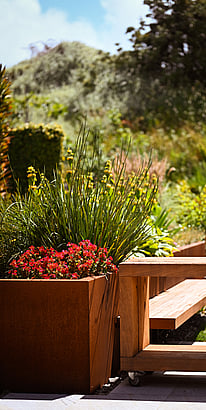 Beautifully planted corten raised planter with built-in seating and moveable outdoor counters
