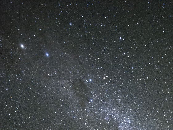 Man standing outside at night pointing up at the milky way in the night sky