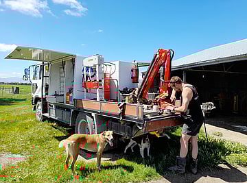 Andy from AEM working onsite in the Maniototo sunshine with cheerful four-legged helpers.