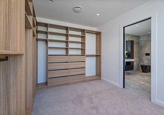 Inside a walk-in-closet showing custom closet design with Shelves and Drawers in a wood grain effect. 