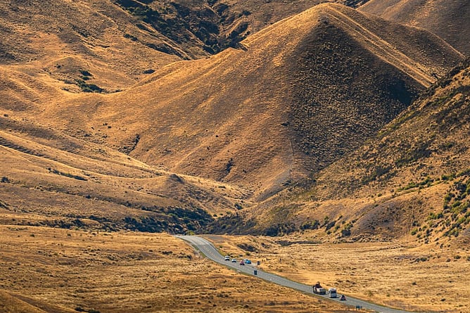 Golden tussock landscape and winding alpine road through Lindis Pass in New Zealand&rsquo;s South Island
