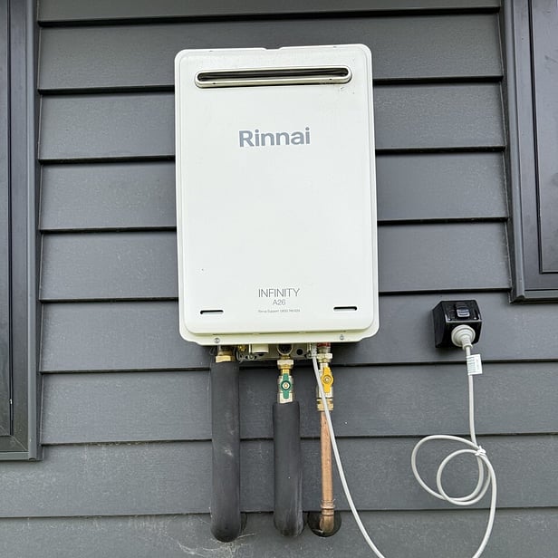 rinnai infinity gas hot water califont on black weatherboard wall