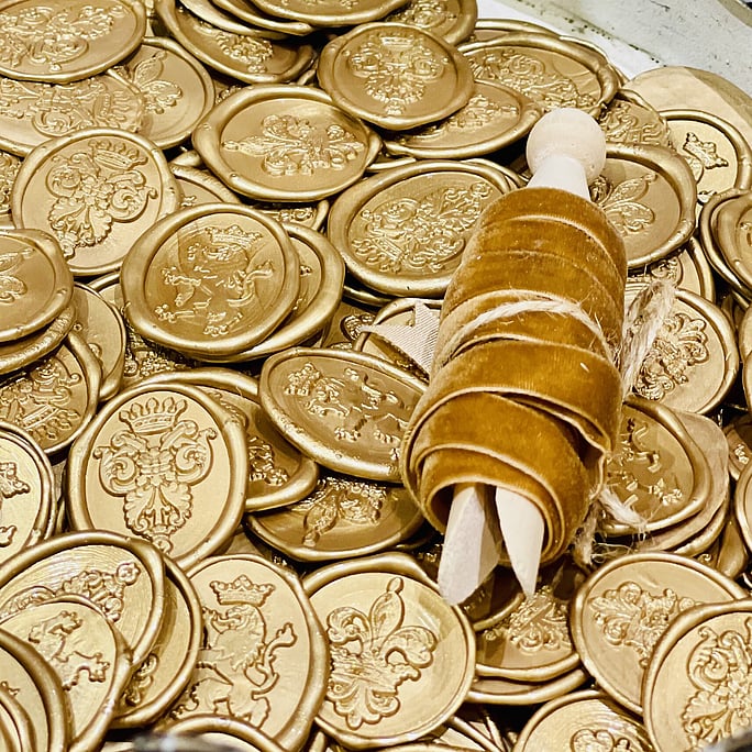 A stack of gold wax seals made by The House of Calligraphy and gold velvet ribbon soon to be available to purchase
