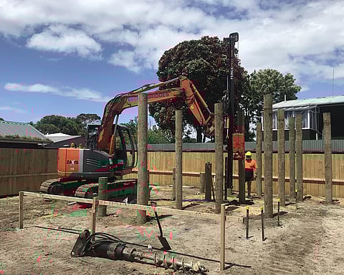 Placing the piles in the predrilled holes, and ramming them into place.