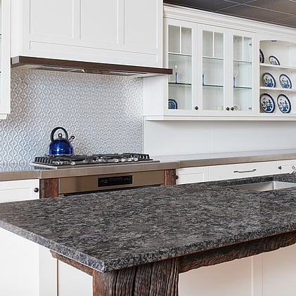 Elegant white kitchen design with glass-front cabinets and a polished stone benchtop, showcased in Barrett Joinery's Timaru showroom to illustrate premium joinery and tailored design.