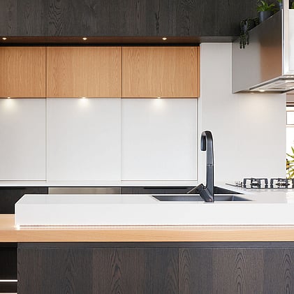 Close-up of sleek black kitchen tap and integrated sink in a modern kitchen display at Barrett Joinery's Timaru showroom, demonstrating high-quality craftsmanship and attention to detail.