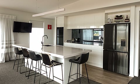 Custom cabinetry with a gloss finish in white, providing a sleek look, crafted by Barrett Joinery.
