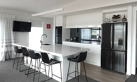 Custom cabinetry with a gloss finish in white, providing a sleek look, crafted by Barrett Joinery.