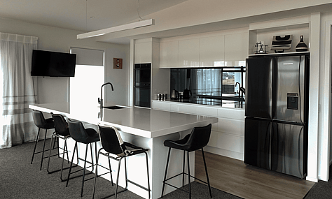 Custom cabinetry with a gloss finish in white, providing a sleek look, crafted by Barrett Joinery.