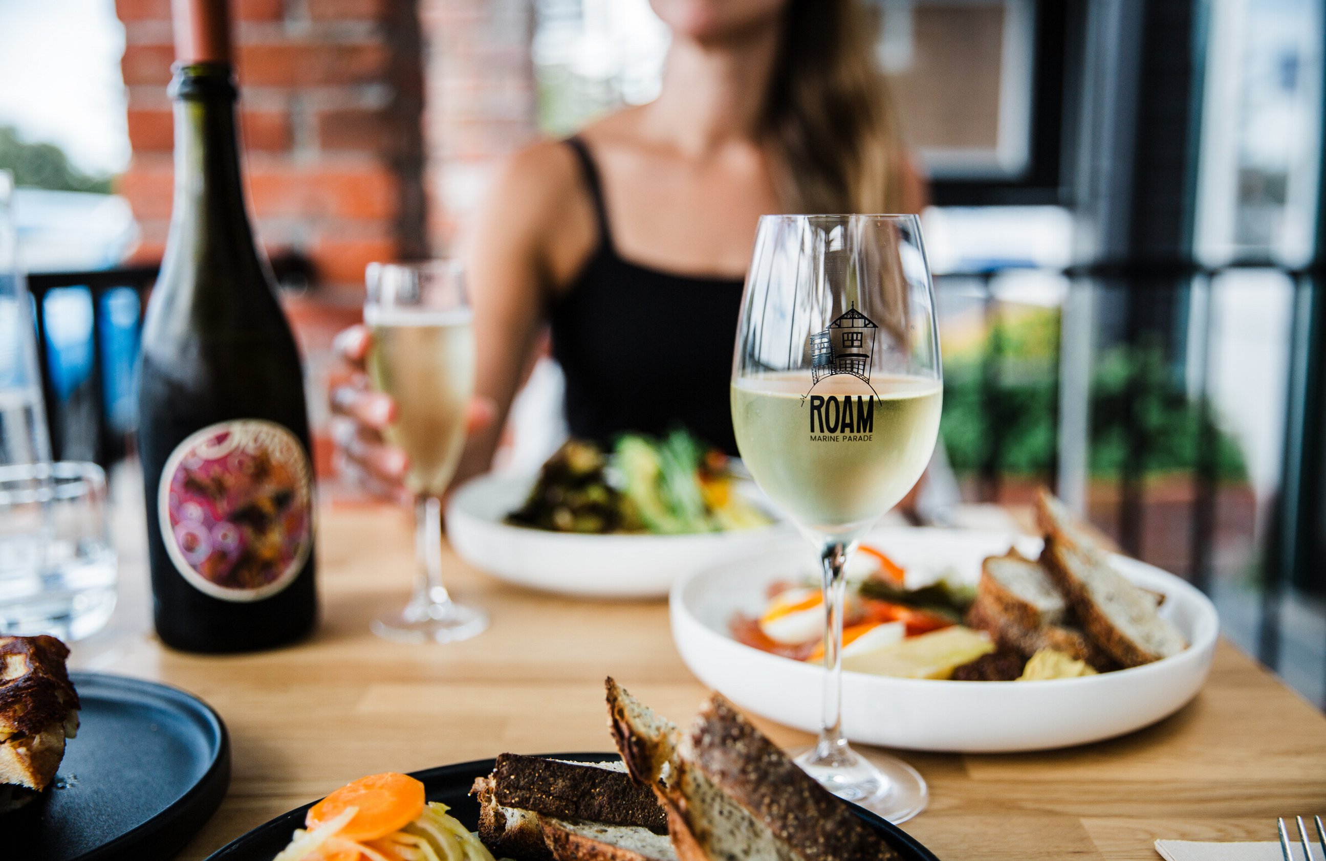 Image of people enjoying great food and wine at ROAM Marine Parade cafe in Napier, Hawkes Bay. New Zealand. 