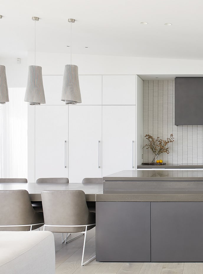 Polished stone kitchen island with extended dining table and modern grey leather chairs