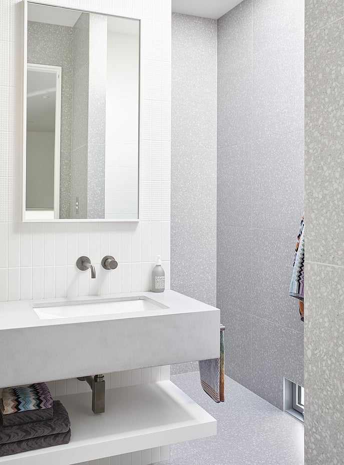 White stone bathroom vanity against white vertical tiles and full height tiled shower