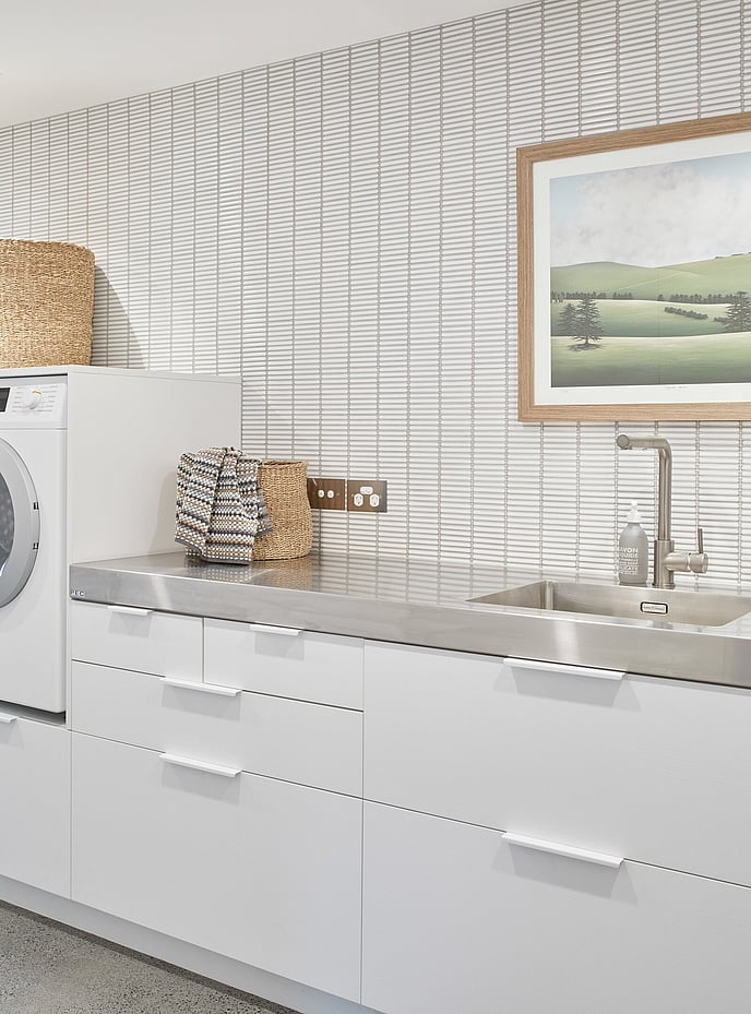 Laundry cabinetry with stainless steel benchtop and white mosaic tiling 