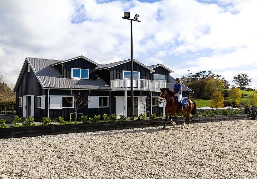 Lady riding a horse in an arena passed the Newbury barn
