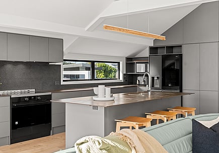 After image of a new kitchen renovation with modern grey units and kitchen island and timber flooring.